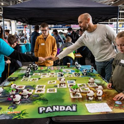 Visiteurs jouant au jeu de plateau Pandai au Festival du jeu de Pau